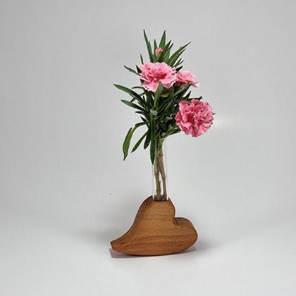 Herz aus Holz liegend mit Vase