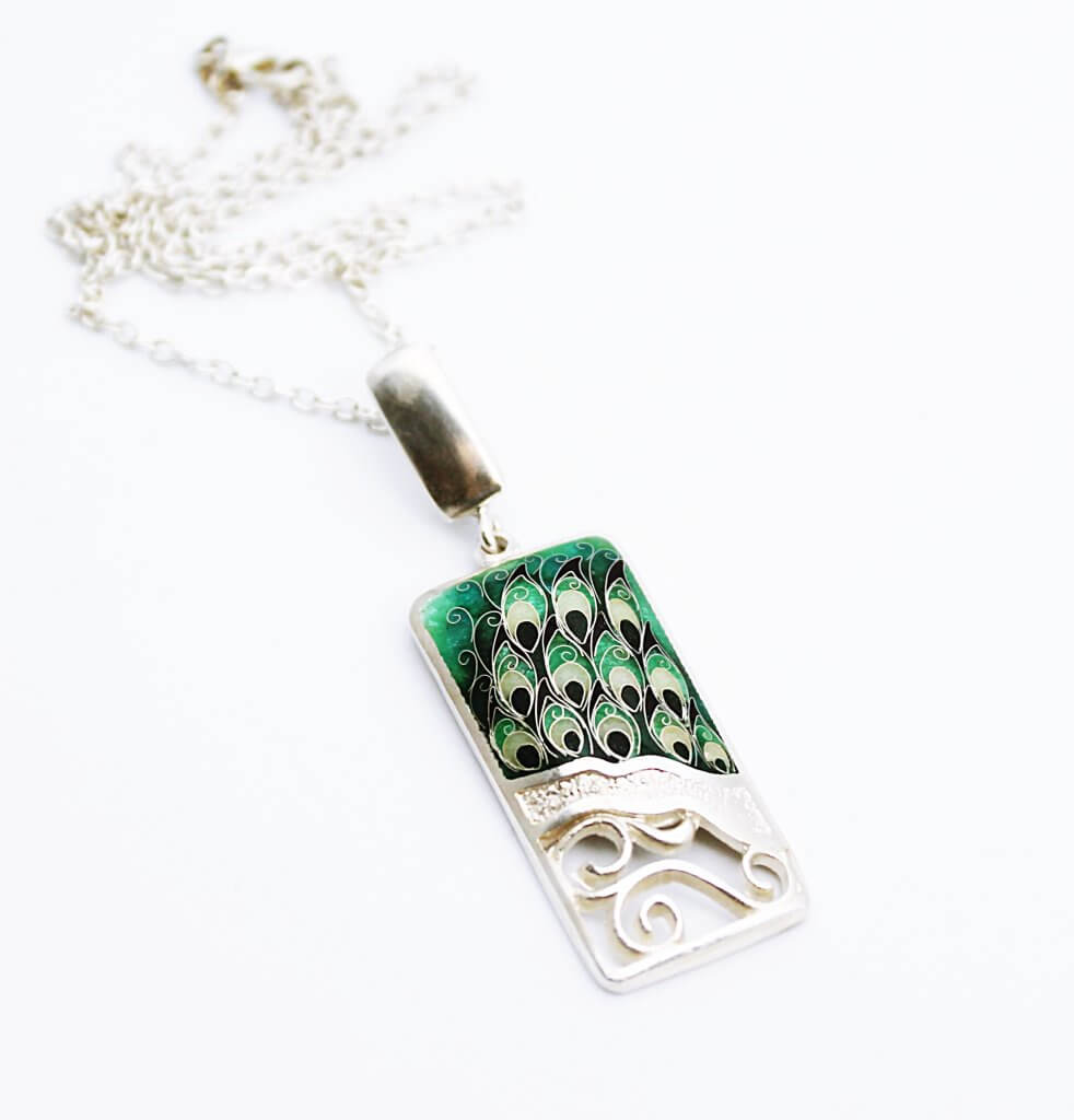 Ein Cloisonne Emaille handgefertigter Anhänger "Pfau" mit Halskette ist ein atemberaubendes Schmuckstück. Cloisonne Emaille ist eine traditionelle Emailletechnik, bei der Metallkanten verwendet werden, um verschiedene Farben voneinander zu trennen und ein Muster zu bilden. Der Pfau ist ein Symbol für Schönheit, Anmut und Wohlstand, und der Anhänger verkörpert diese Eigenschaften auf kunstvolle Weise. Mit der dazugehörigen Halskette wird der Anhänger stilvoll präsentiert und kann jedes Outfit ergänzen. Ein Cloisonne Emaille Anhänger "Pfau" mit Halskette ist ein faszinierendes Schmuckstück, das sowohl eine ästhetische als auch eine symbolische Bedeutung hat. Es ist ein wahrer Blickfang und ein Ausdruck von Eleganz und Stil.